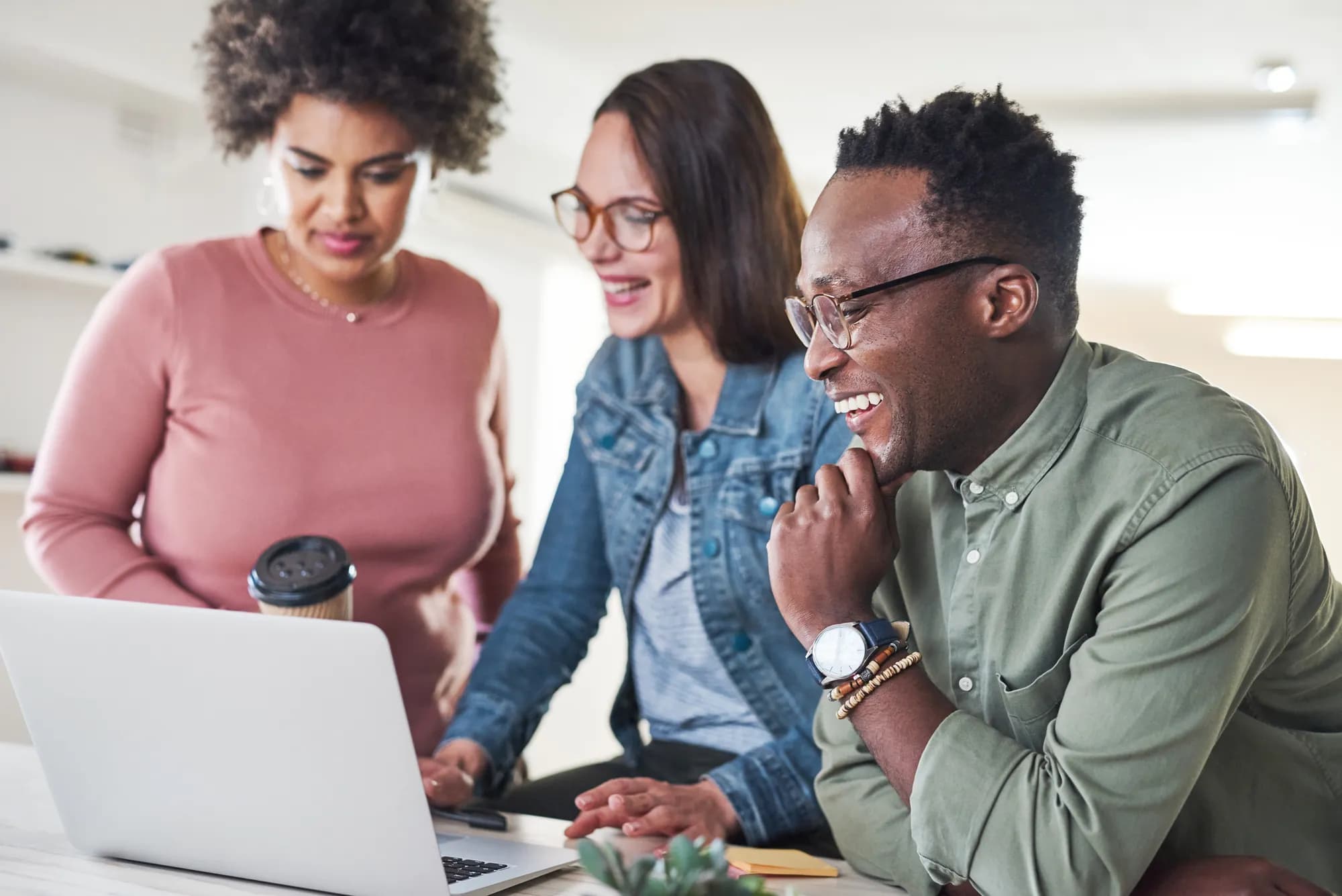 A small team collaborating around a laptop in a bright office